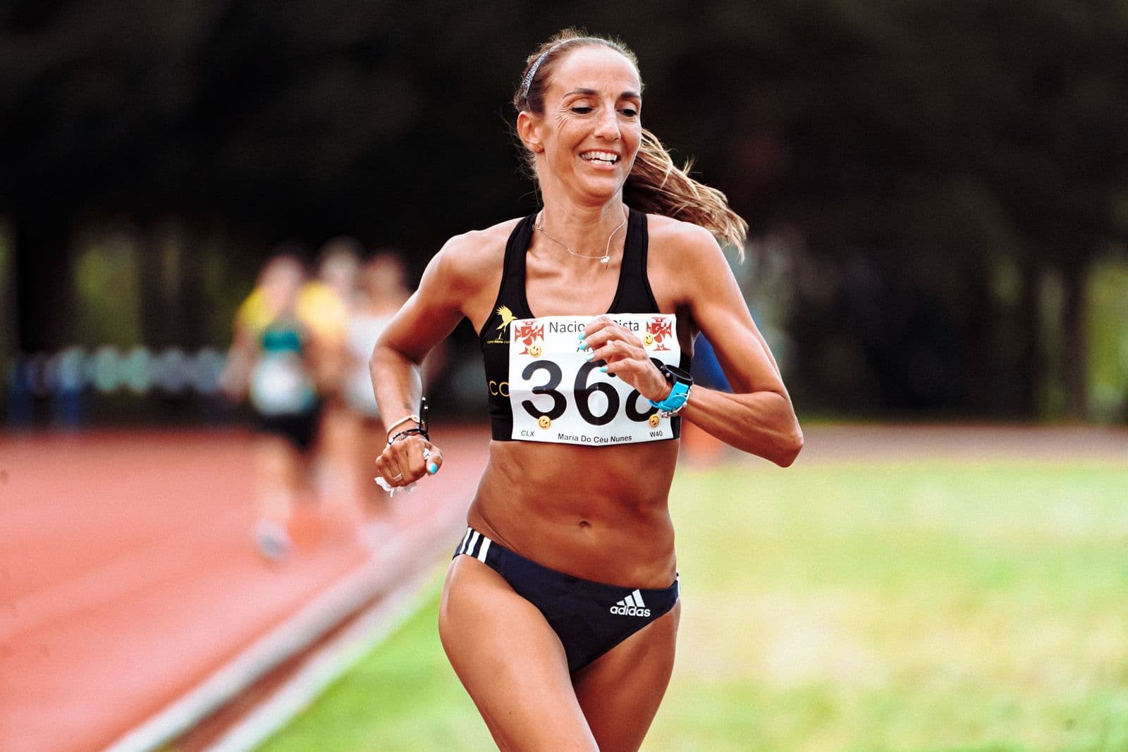 A smiling athlete competing on an outdoor running track